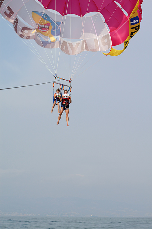 An adult and a student in the air parasailing 