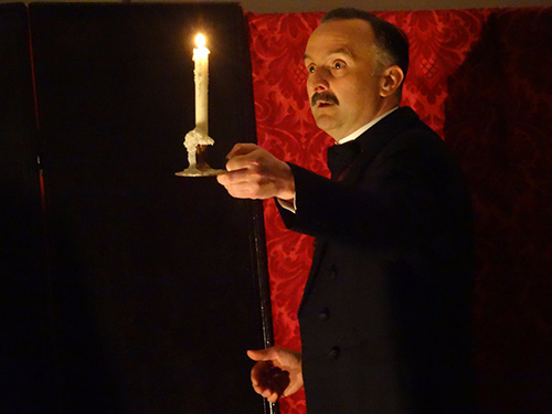 An actor is holding a candle while performing a play